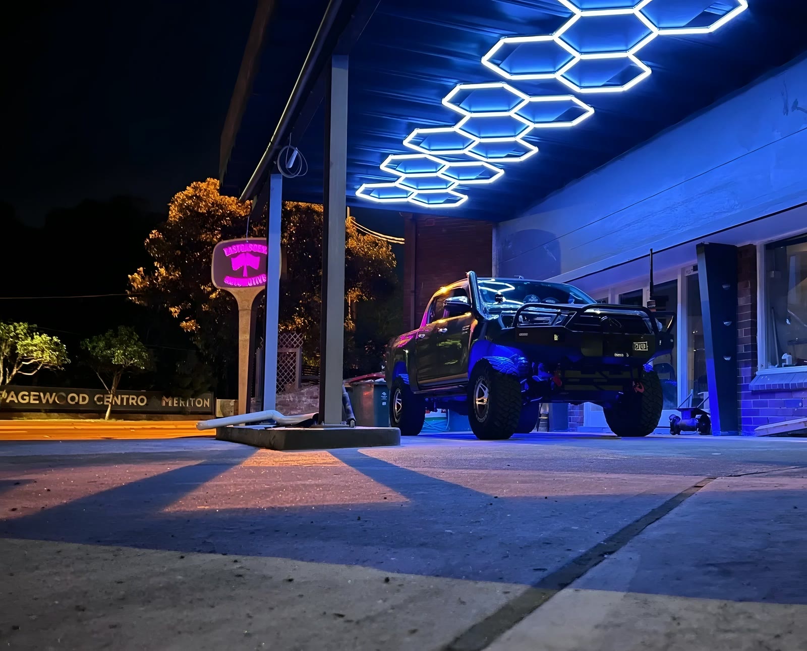 The Eastgardens Automotive workshop at night under hexagon lights